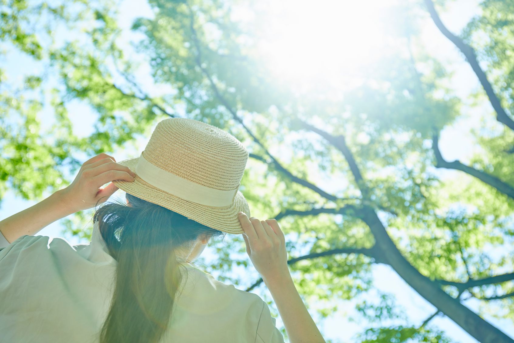 Woman looking at sun wearing a hat practicing UV safety measures