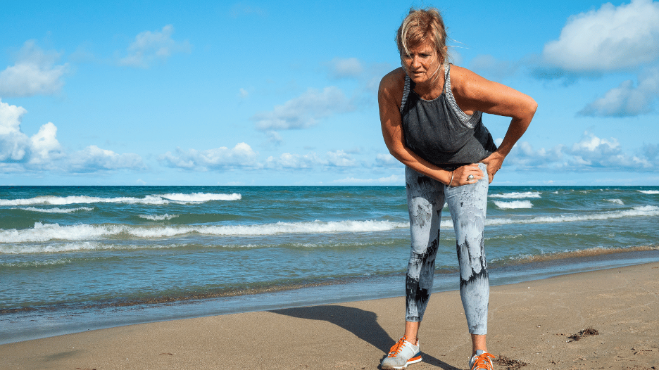 Woman with hip dysplasia pain standing on a beach