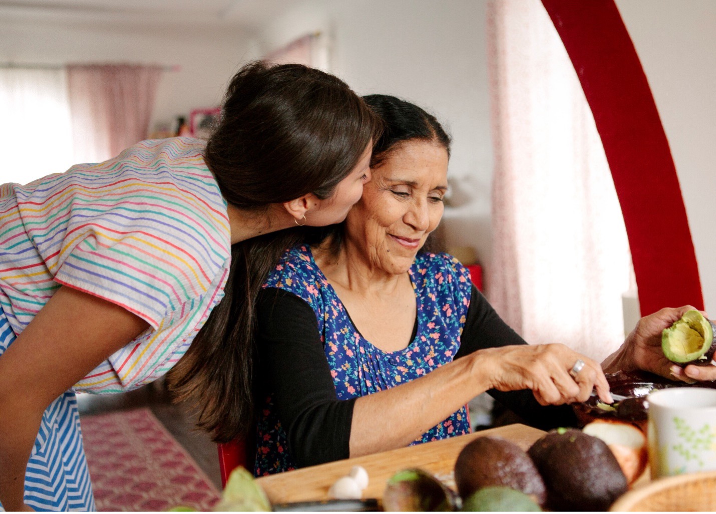 Daughter kissing her elderly mother in the kitchen, highlighting care and support for choosing the right C-SNP Medicare plan