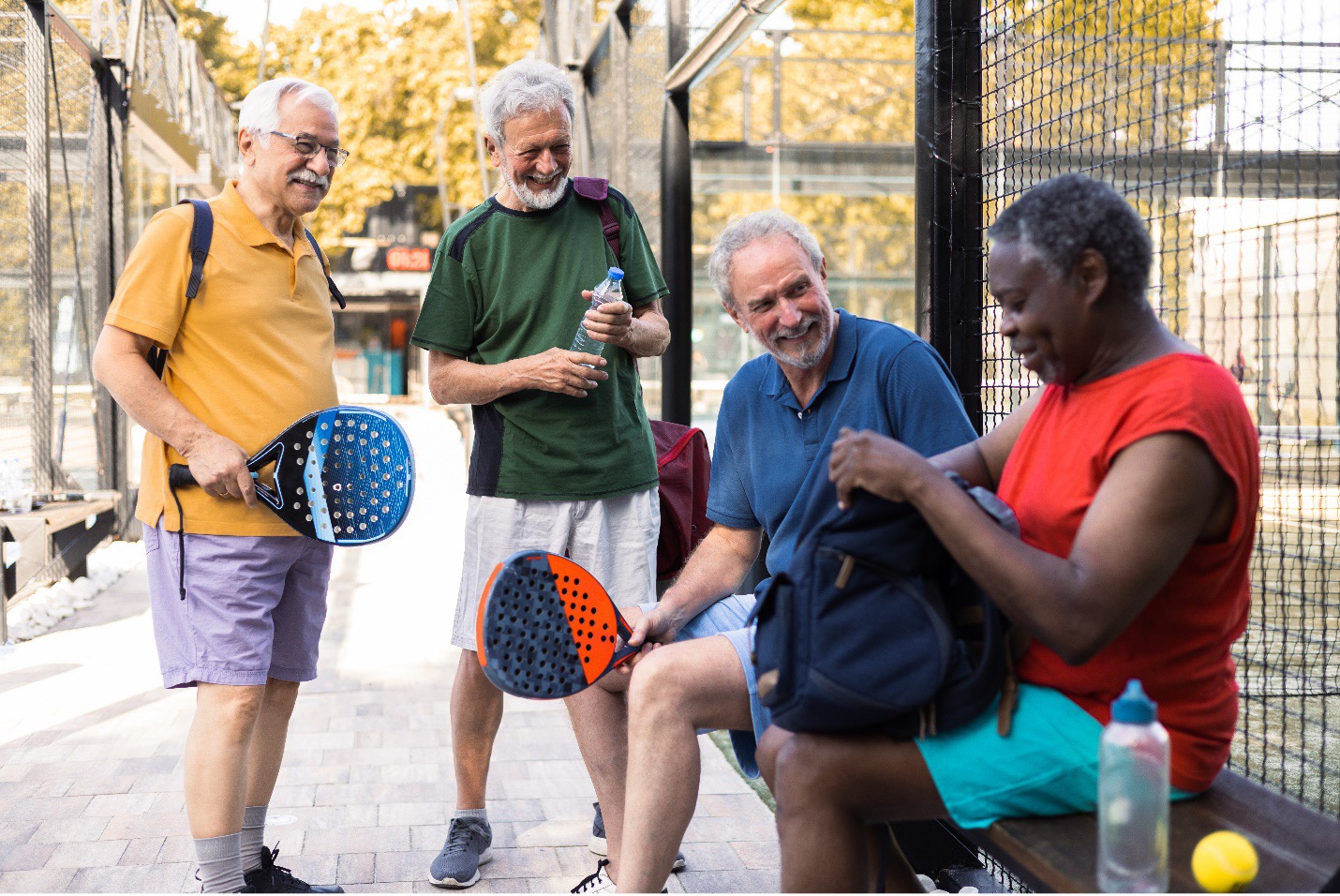 Four older adults at a tennis court, representing active lifestyles supported by Medicare drug coverage