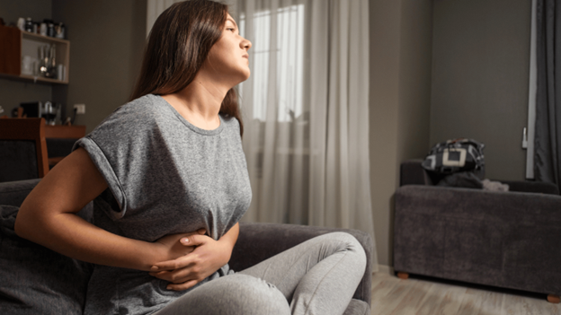 Woman experiencing painful gallbladder issues on a bed.