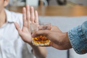 Person holding a hand up to reject an alcoholic drink