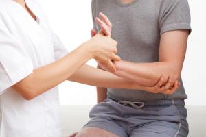 A hand therapist massaging someone's wrist and elbow