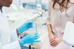 A doctor wearing blue glove showing a patient how STD testing works on a cotton swab