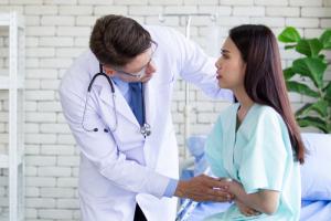 Doctor helping woman suffering from a hernia in the exam room