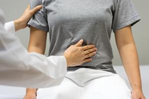 Gastroenterologist checking a woman's stomach for abdominal pain due to pandemic tummy