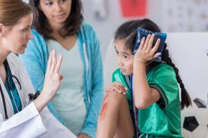 Doctor helping treat a young girl exhibiting concussion symptoms after a physical injury