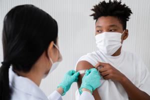 Female doctor applying a bandage to a patient's arm after administering a flu shot.