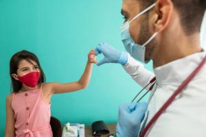 Young girl with congenital heart disease forming the shape of a heart with her hands with her doctor