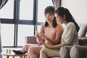 Mother and daughter sitting on couch monitoring blood sugar levels 