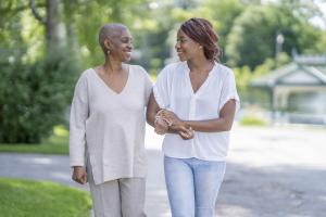 Two women, one with alopecia hair loss, walking and smiling