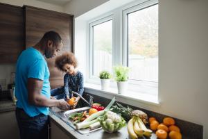 Father and daughter taking part in nutrition services  rinsing off vegetables in the kitchen