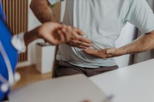 Closeup of a patient grasping stomach after experiencing peptic ulcer symptoms