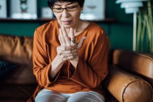 woman massaging her hand after experiencing trigger finger symptoms