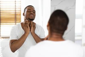 man feeling swollen lymph nodes under his jaw