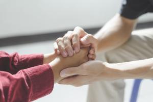 Person holding hands and comforting family member with depression