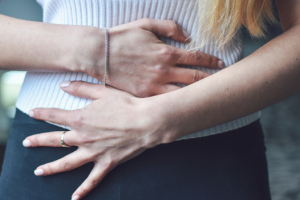 A woman experiencing pelvic pain gripping her abdomen