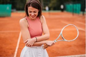 Woman holding an injured elbow playing tennis