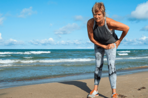 Woman with hip dysplasia pain standing on a beach