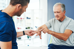 An older man consults with a Summit Health physical therapist about preventing arthritis in his hands, focusing on pain management and improving joint function