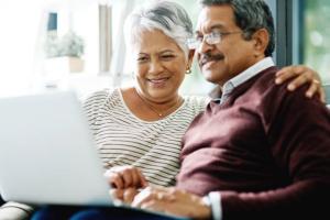 Elderly couple sitting down together with a laptop to explore their options for Medicare plans