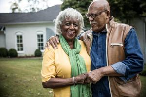 Elderly couple standing together in front of their home, symbolizing stability and preparedness during the Medicare Annual Enrollment Period