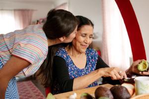 Daughter kissing her elderly mother in the kitchen, highlighting care and support for choosing the right C-SNP Medicare plan