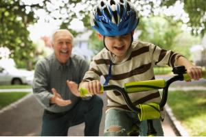 Grandfather cheering on his grandchild learning to ride a bike, symbolizing guidance and support for navigating 2025 Medicare changes.