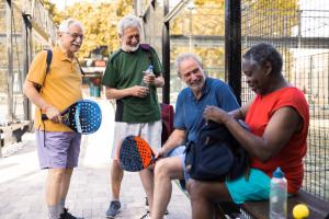 Four older adults at a tennis court, representing active lifestyles supported by Medicare drug coverage