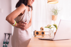 A woman grasping her side, experiencing appendicitis pain in her abdomen