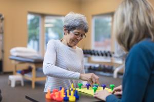 A woman performing hand therapy exercises at Summit Health with therapy toys to improve hand mobility