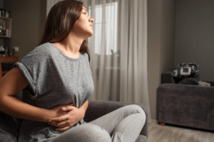 Woman experiencing painful gallbladder issues on a bed.